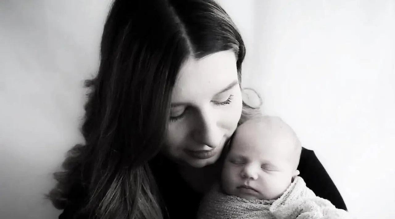 Mother holding her sleeping newborn in soft light